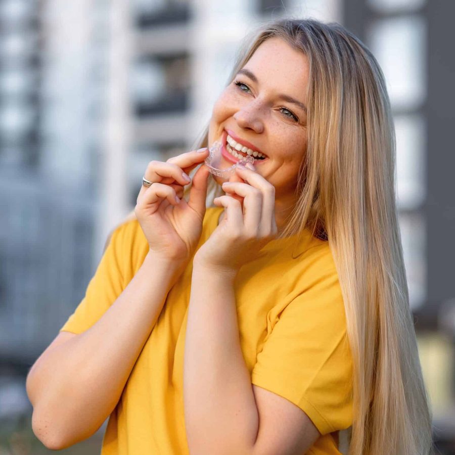 A,Young,Woman,Joyfully,Using,Clear,Aligners,Outdoors,,Surrounded,By